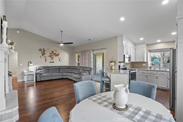 dining room with ceiling fan, sink, dark hardwood / wood-style floors, and lofted ceiling