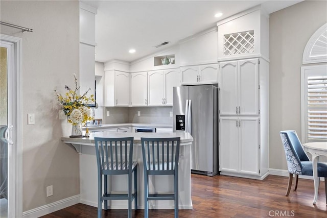 kitchen with a breakfast bar area, kitchen peninsula, white cabinetry, and stainless steel fridge