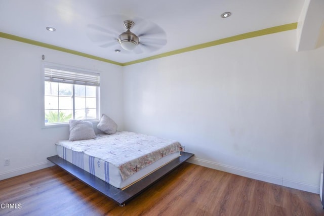 bedroom with ornamental molding, dark wood-type flooring, and ceiling fan