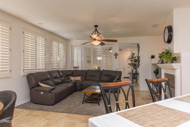 living room featuring a tiled fireplace and ceiling fan