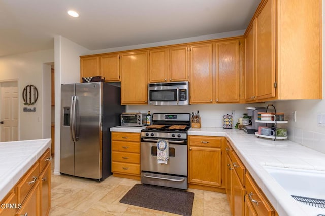 kitchen with tile counters and appliances with stainless steel finishes