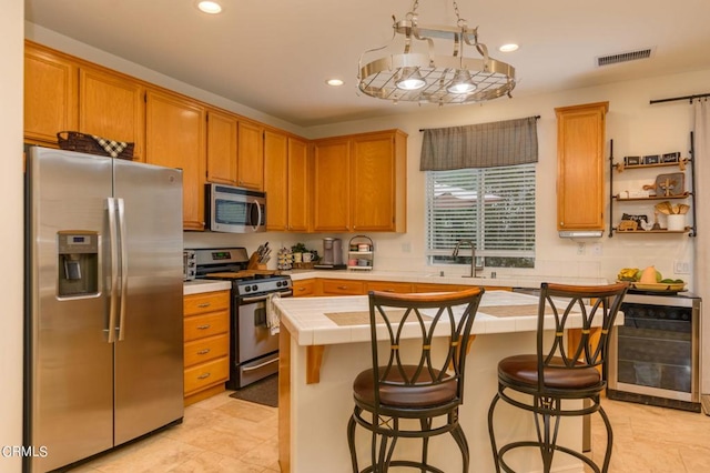 kitchen featuring a kitchen breakfast bar, stainless steel appliances, a center island, tile countertops, and beverage cooler