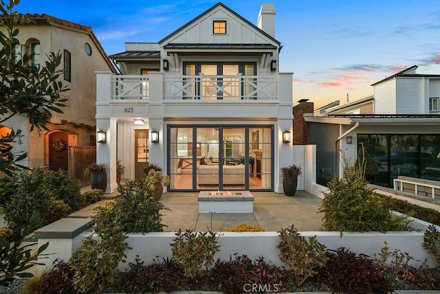 back house at dusk with french doors and a balcony