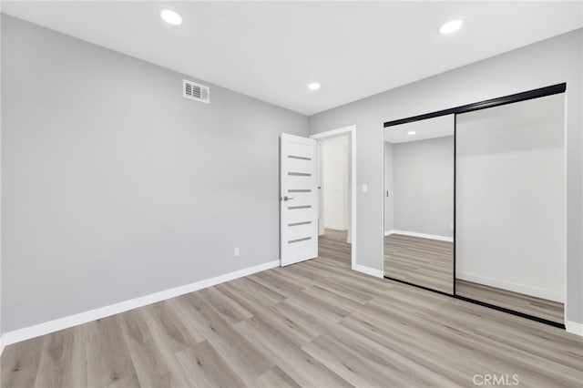 unfurnished bedroom with light hardwood / wood-style floors and a closet