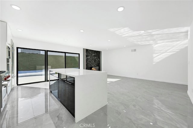 kitchen featuring a premium fireplace, a kitchen island, and white cabinets