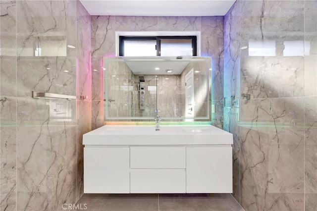 bathroom with walk in shower, vanity, and tile walls