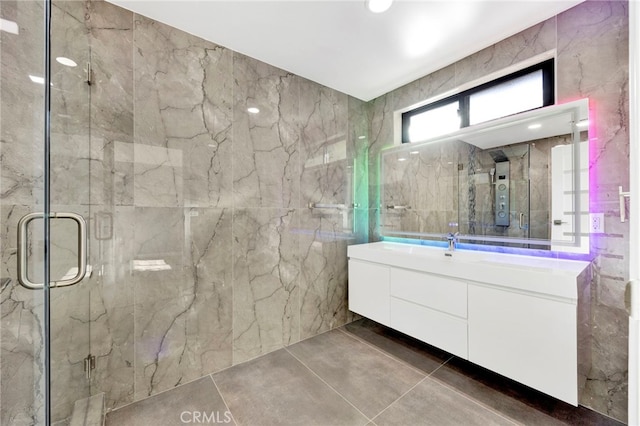 bathroom with walk in shower, tile patterned floors, vanity, and tile walls