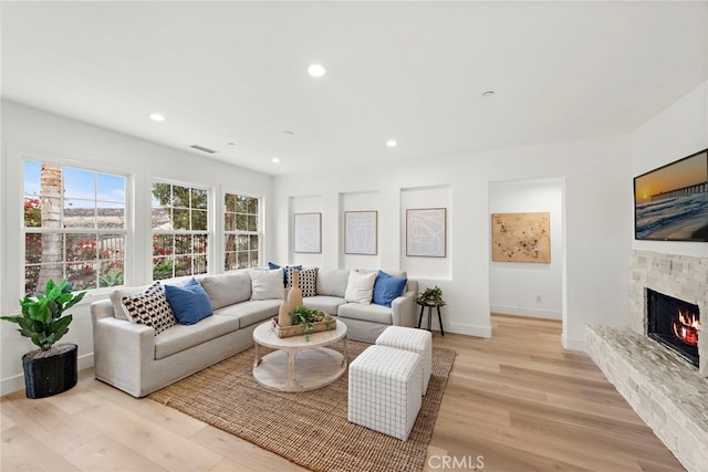 living room featuring a stone fireplace and light wood-type flooring