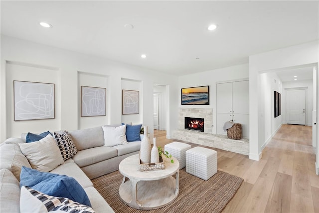 living room with a stone fireplace and light hardwood / wood-style flooring