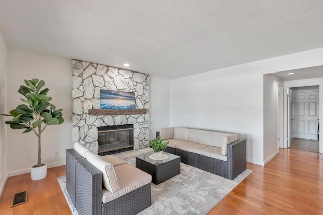 living room featuring hardwood / wood-style flooring, a fireplace, and a textured ceiling