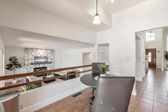 tiled dining area featuring an inviting chandelier, a fireplace, and a high ceiling