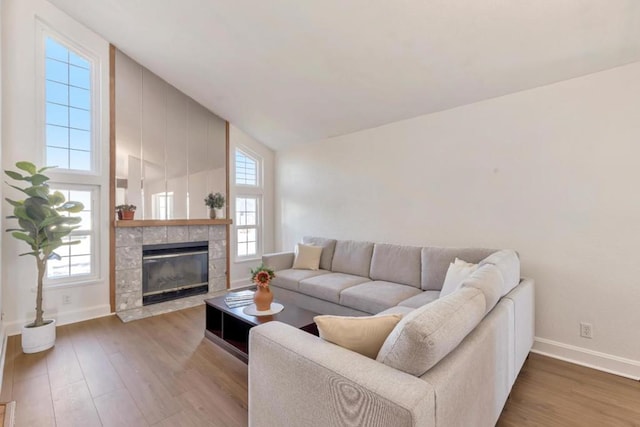 living room featuring hardwood / wood-style flooring, a tiled fireplace, and lofted ceiling