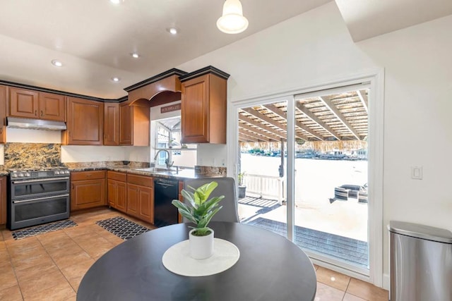 kitchen featuring light tile patterned flooring, dishwasher, sink, dark stone countertops, and range with two ovens