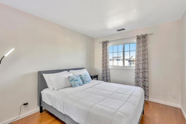 bedroom featuring a textured ceiling and light wood-type flooring