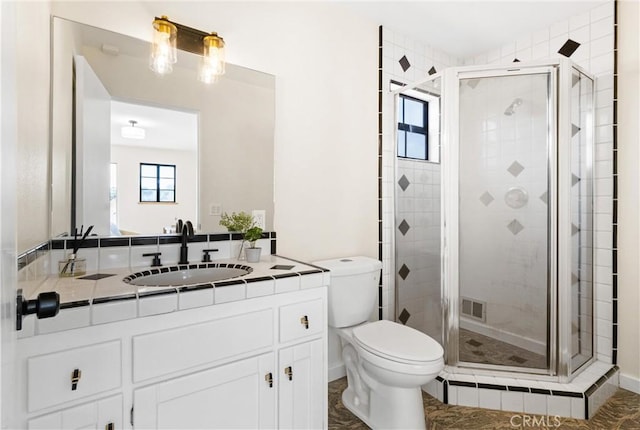 bathroom featuring vanity, a shower with shower door, and toilet