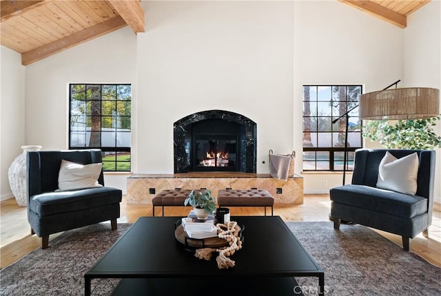 living room with beamed ceiling, a premium fireplace, hardwood / wood-style floors, and wood ceiling