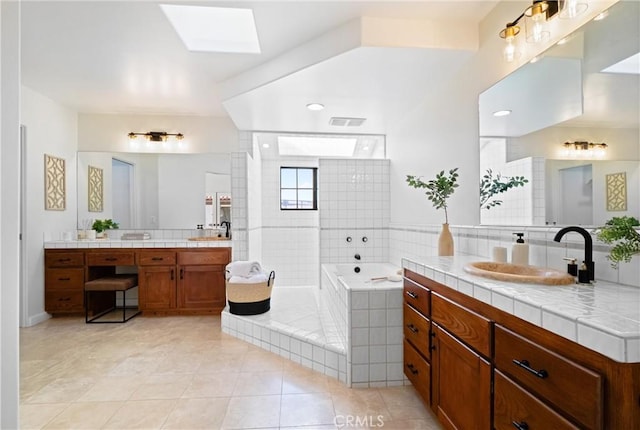 bathroom featuring vanity, shower with separate bathtub, a skylight, and tile patterned flooring