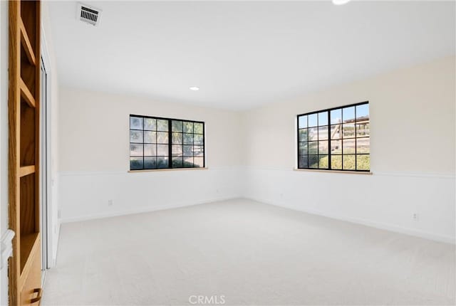 empty room featuring light colored carpet and a healthy amount of sunlight