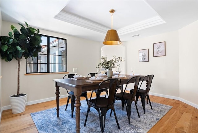 dining area with a raised ceiling and hardwood / wood-style floors