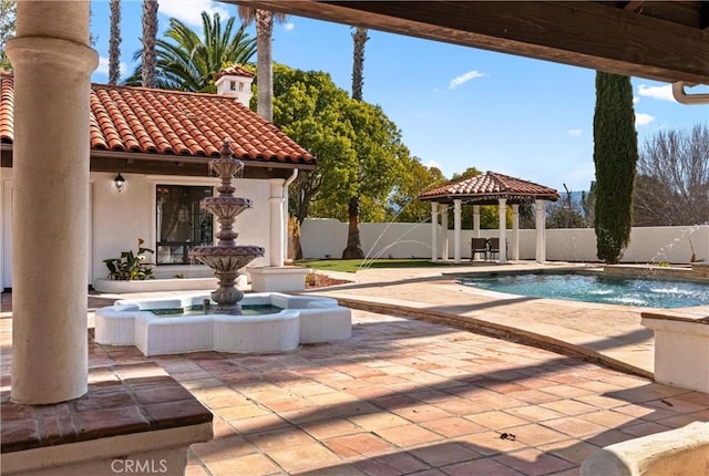 view of swimming pool featuring a gazebo, pool water feature, an in ground hot tub, and a patio