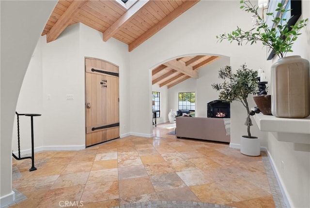 entryway featuring beam ceiling, wood ceiling, a skylight, and high vaulted ceiling