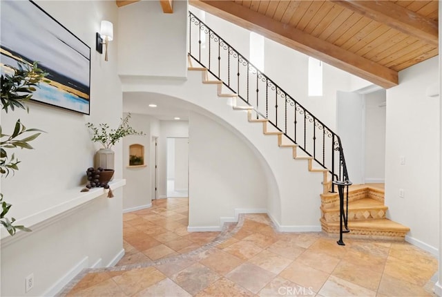 stairs featuring beamed ceiling, a towering ceiling, and wood ceiling