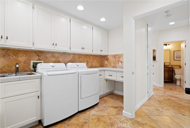 clothes washing area with cabinets, separate washer and dryer, and sink