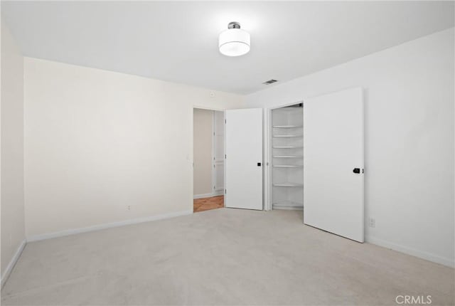 unfurnished bedroom with light carpet and a closet