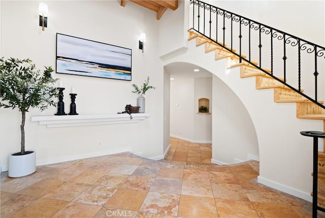 foyer featuring beamed ceiling and a high ceiling