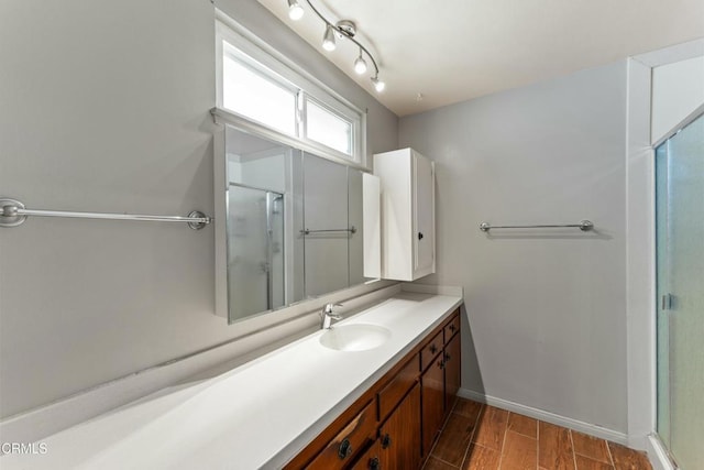 full bath featuring a stall shower, wood tiled floor, baseboards, and vanity