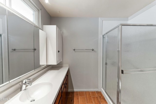 bathroom with wood tiled floor, baseboards, vanity, and a shower stall