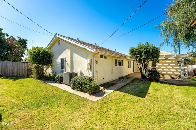 back of property featuring a yard, fence, cooling unit, and stucco siding