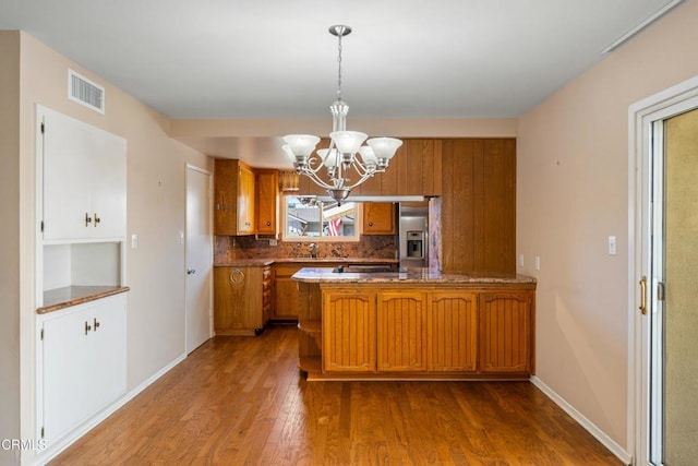 kitchen featuring wood finished floors, visible vents, stainless steel refrigerator with ice dispenser, brown cabinetry, and pendant lighting