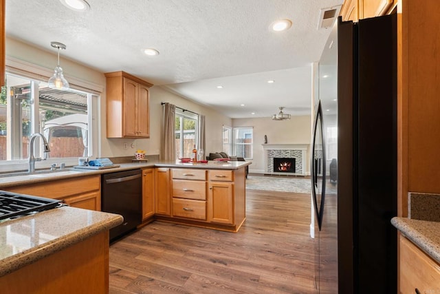 kitchen featuring a textured ceiling, hanging light fixtures, dark hardwood / wood-style flooring, kitchen peninsula, and black appliances