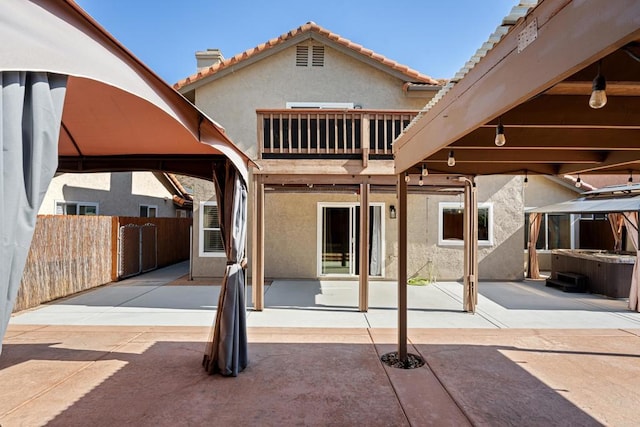 back of property featuring a gazebo, a balcony, and a patio