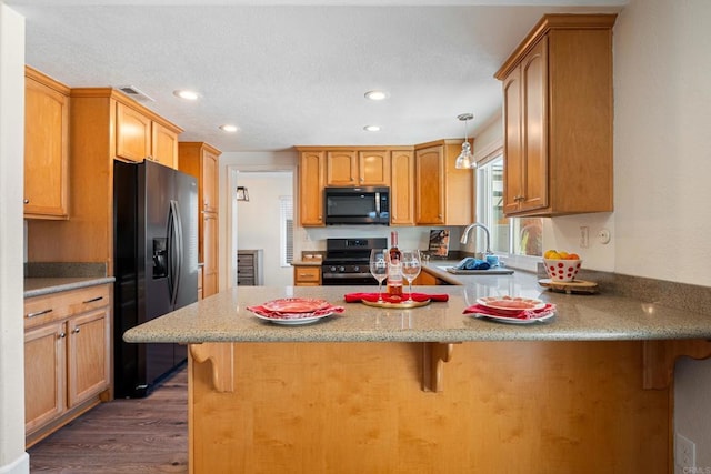 kitchen with a breakfast bar, sink, range, black refrigerator with ice dispenser, and kitchen peninsula