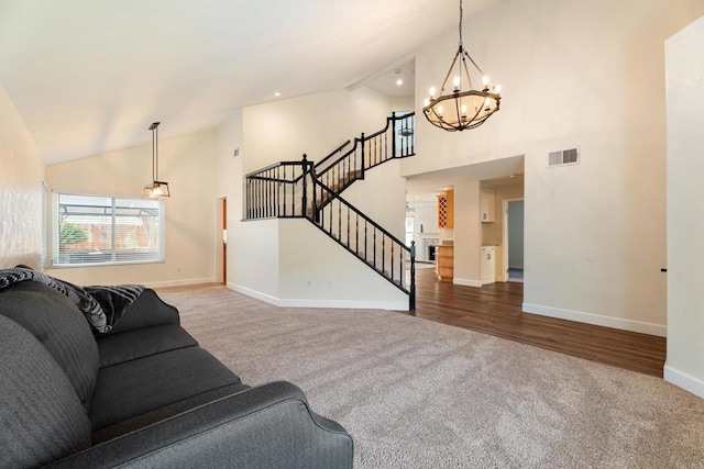 carpeted living room with a notable chandelier and high vaulted ceiling