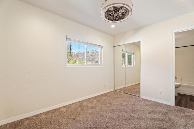 unfurnished bedroom featuring ensuite bath and carpet