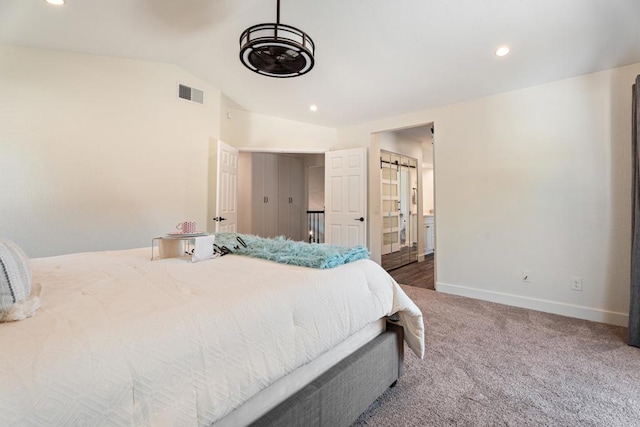 carpeted bedroom with vaulted ceiling, a barn door, and ensuite bathroom