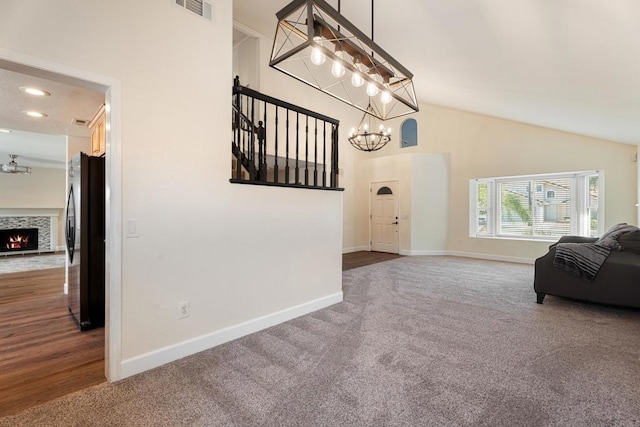 interior space with high vaulted ceiling, a chandelier, and dark colored carpet