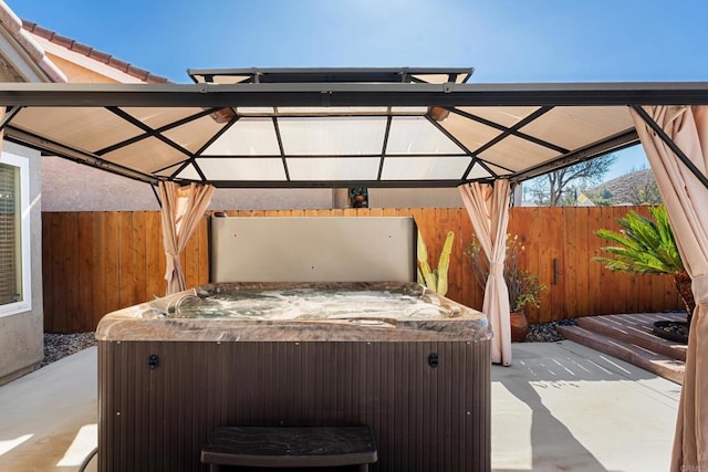 view of patio / terrace featuring a hot tub and a gazebo