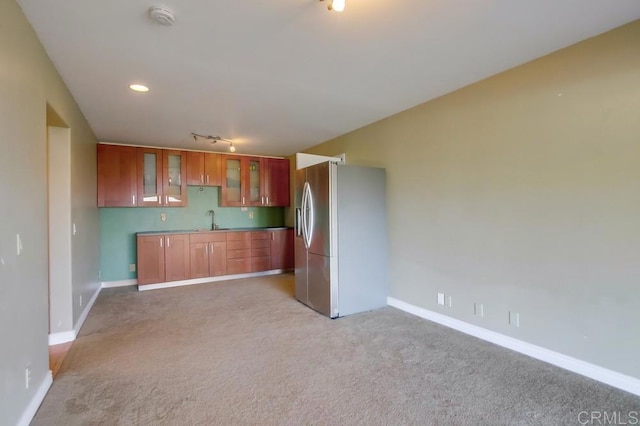 kitchen with sink, light carpet, track lighting, and stainless steel refrigerator