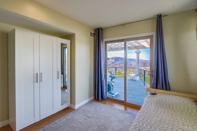 unfurnished bedroom with a mountain view, access to exterior, light hardwood / wood-style floors, and a closet