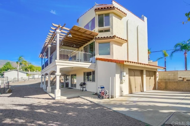 back of property with a tiled roof, fence, a balcony, and stucco siding