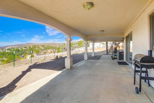 view of patio / terrace featuring cooling unit, a mountain view, stairway, and fence