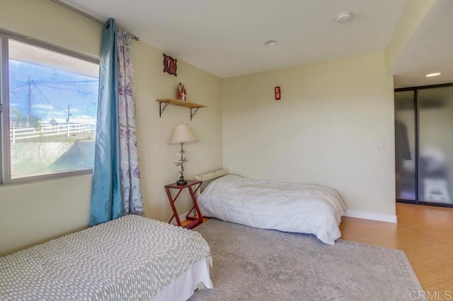 bedroom featuring light wood-style floors, multiple windows, and baseboards