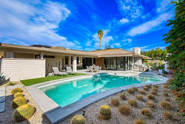 rear view of property with a fenced in pool and a patio