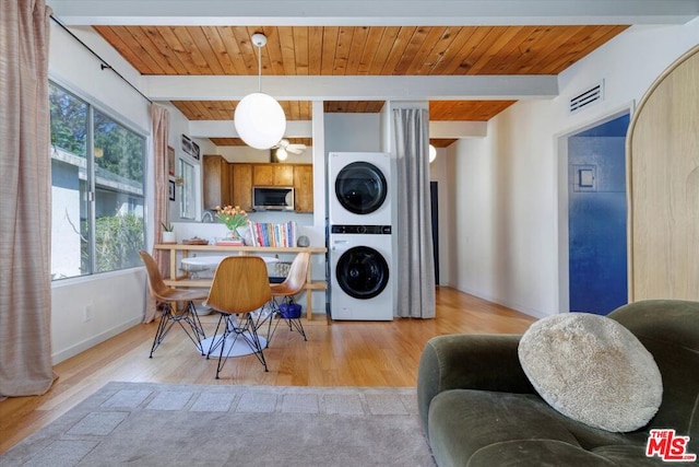 dining space with wood ceiling, stacked washer / drying machine, beam ceiling, and light hardwood / wood-style flooring