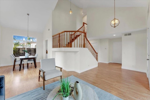 living room featuring high vaulted ceiling, light hardwood / wood-style floors, and a notable chandelier