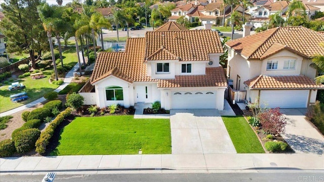 mediterranean / spanish home featuring a garage and a front lawn